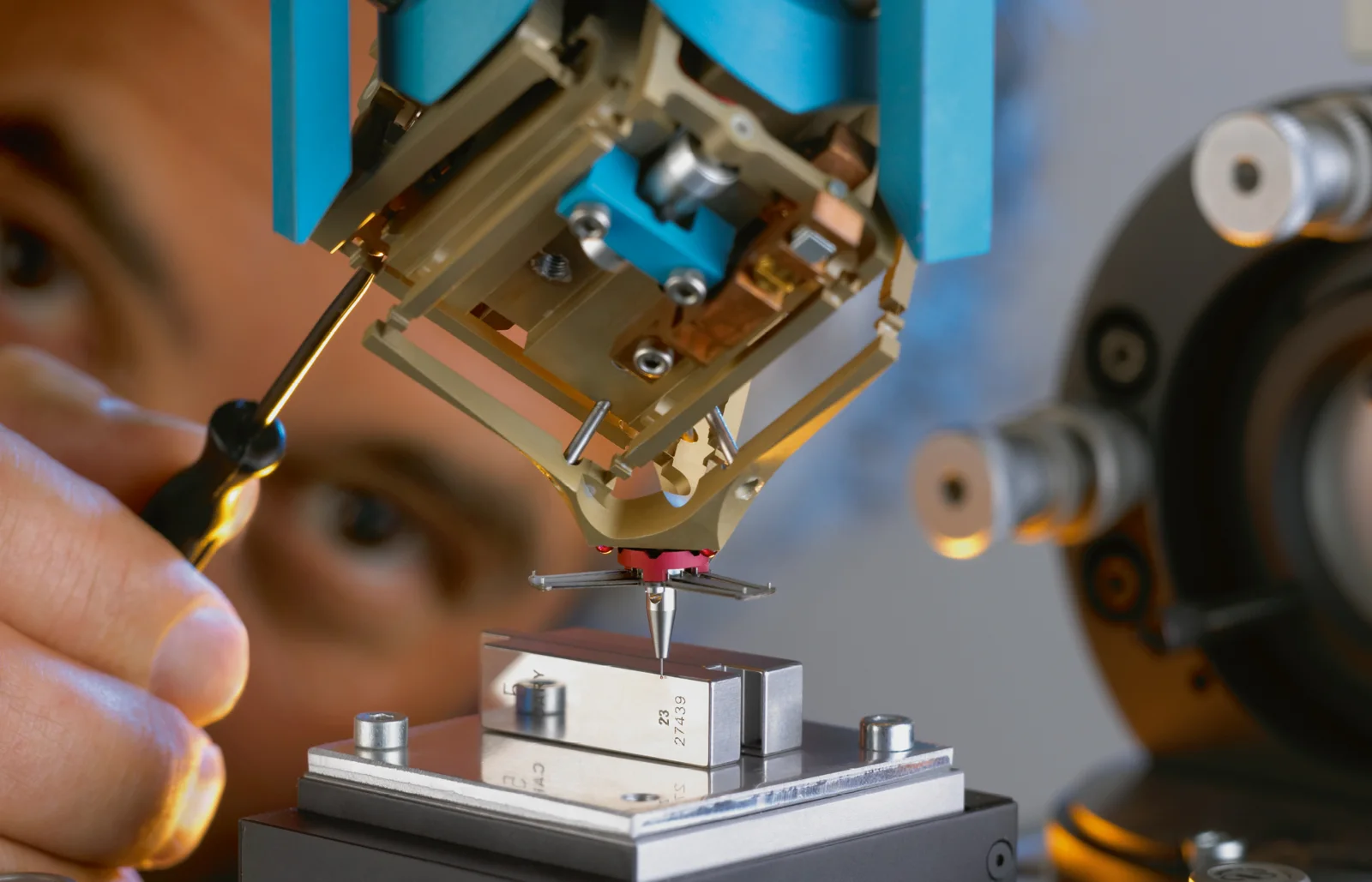 Technician adjusting a flexure-based probe head under a microscope objective
